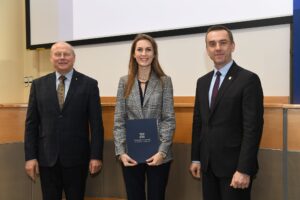 Dwóch mężczyzn i kobieta w szarej marynarce pozuje do zdjęcia.