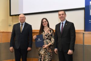 Dwóch mężczyzn i kobieta w kolorowej sukience pozuje do zdjęcia.