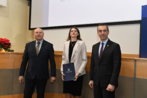 Dwóch mężczyzn i kobieta w jasnej marynatce pozują do zdjęcia