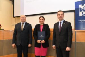 Dwóch mężczyzn i kobieta w różowej sukience pozują do zdjęcia.