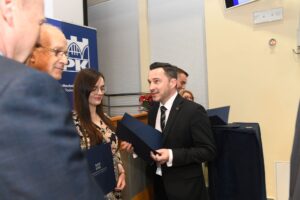 Elegancko ubrany mężczyzna z dyplomem w ręce.