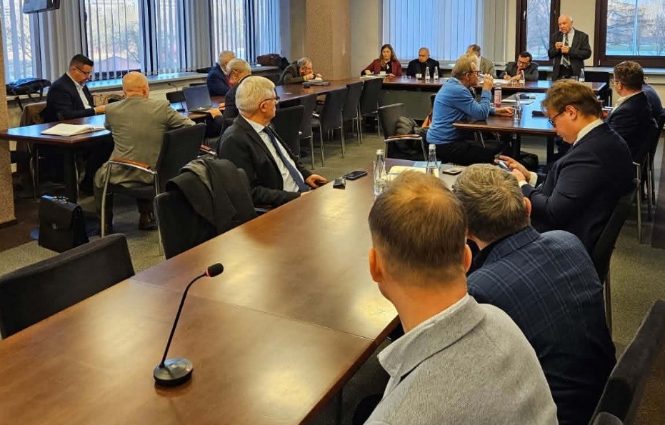 przy stole siedzący ludzie, słuchają wystąpienia